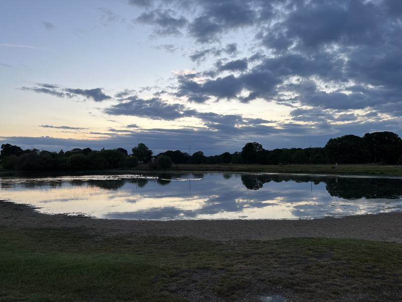 Clouds reflected in Rushmere pond at dusk